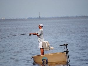 A guy catching a fish from a tan round boat