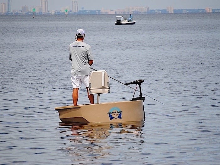 A guy fishing from a tan round boat