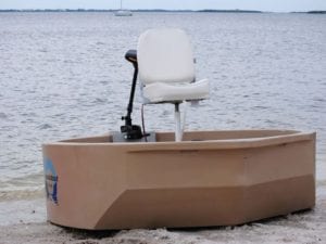 A tan round boat with a front view on the shore