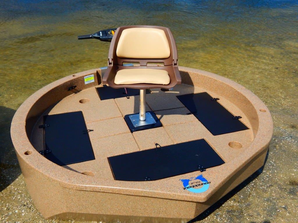 This is a top view of a sandstone colored round boat with white trim sitting on the shore