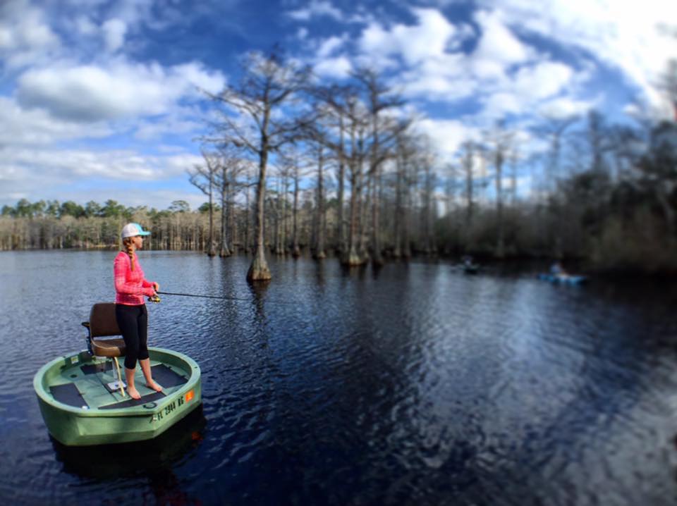 A female fisherman fishing the backwatrs of north florida while standing on the deck of a green round boat