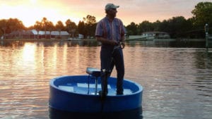 fisherman standing up on the round boat while smiling at sunset