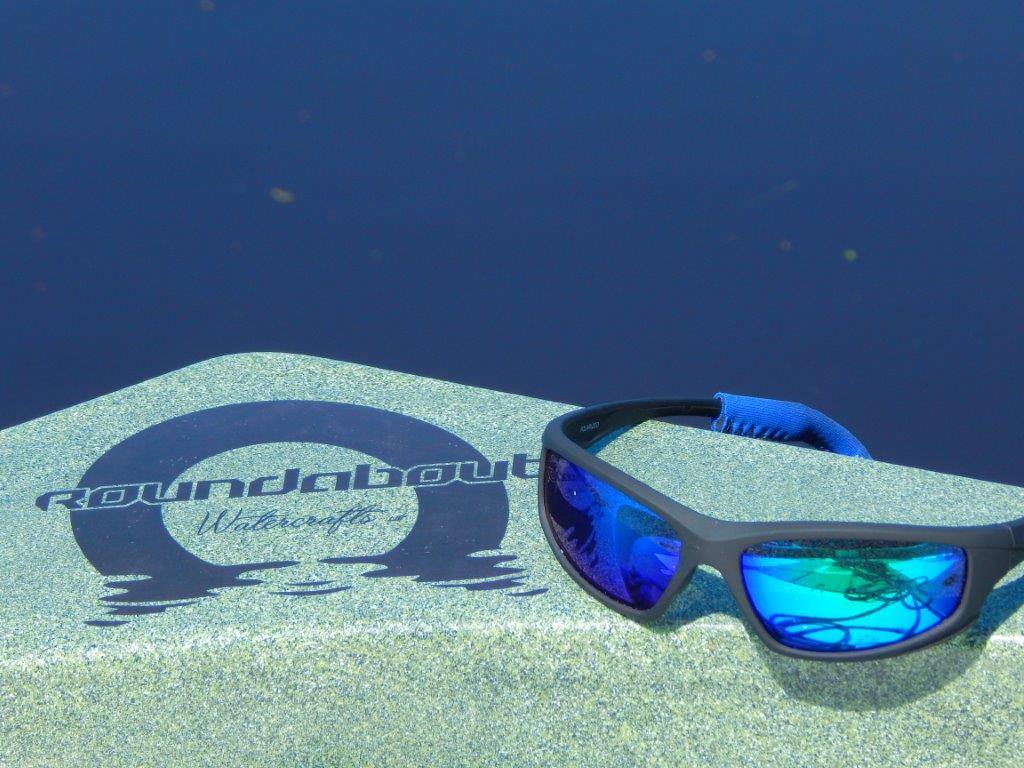 A pair of sunglasses sitting on the deck of the Roundabout Watercrafts round boat.