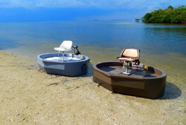 two roundabout watercrafts, the ultraskiff alternative, sitting on the shoreline. One is blue, one is a brown color.