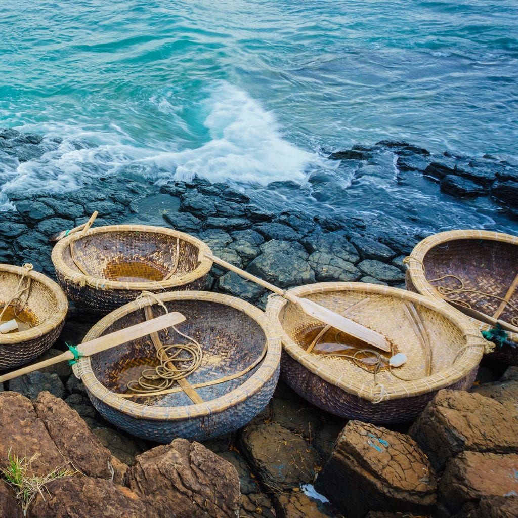 This shows traditional coracle style round boats sitting on a rocky shoreline